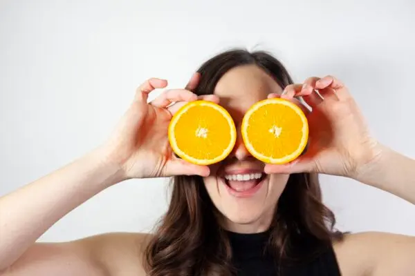 Woman holding oranges up to her eyes.