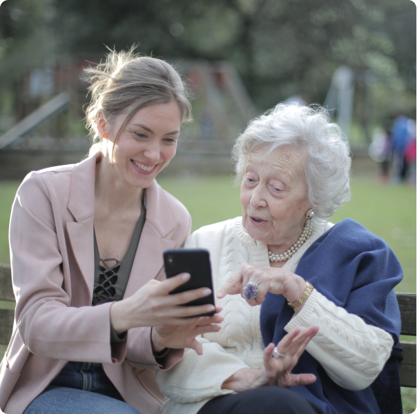 An elderly woman sitting on a bench smiling with her granddaughter