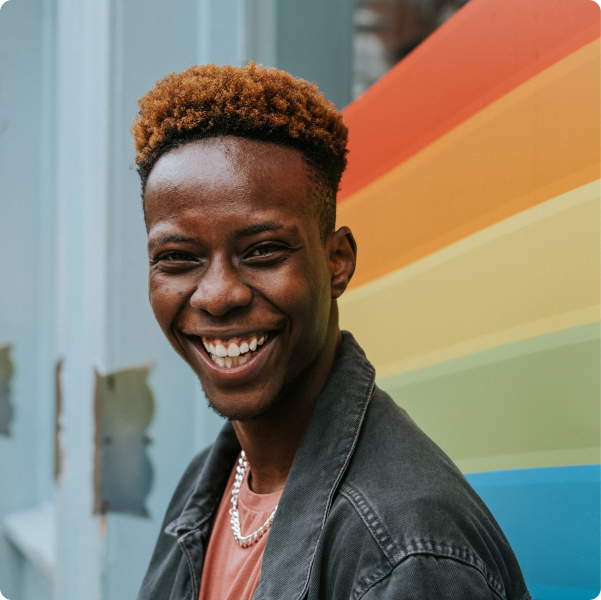 Man smiling in front of a rainbow colored wall