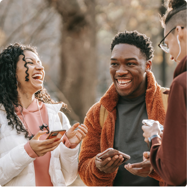 People standing in a group with their phones, laughing and smiling