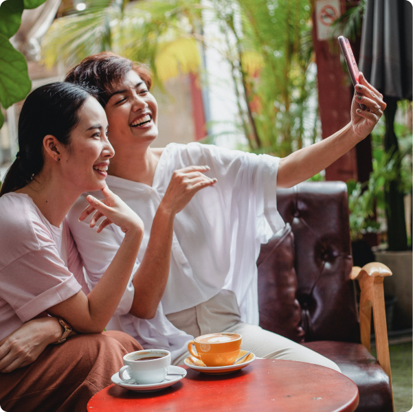 Two women smiling for a selfie together over coffee