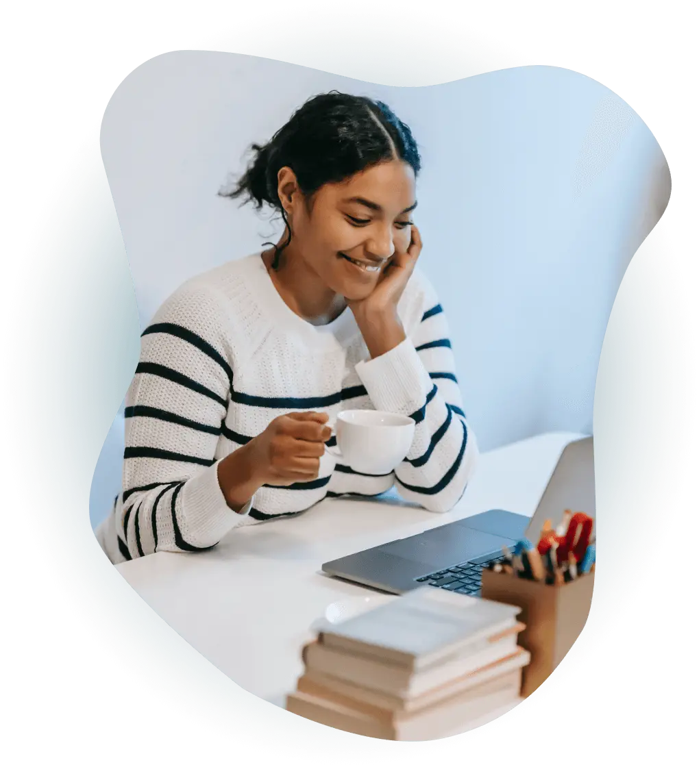 Woman drinking coffee looking at laptop