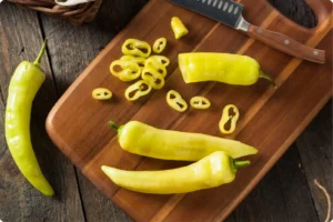 Banana peppers on a cutting board with a knife
