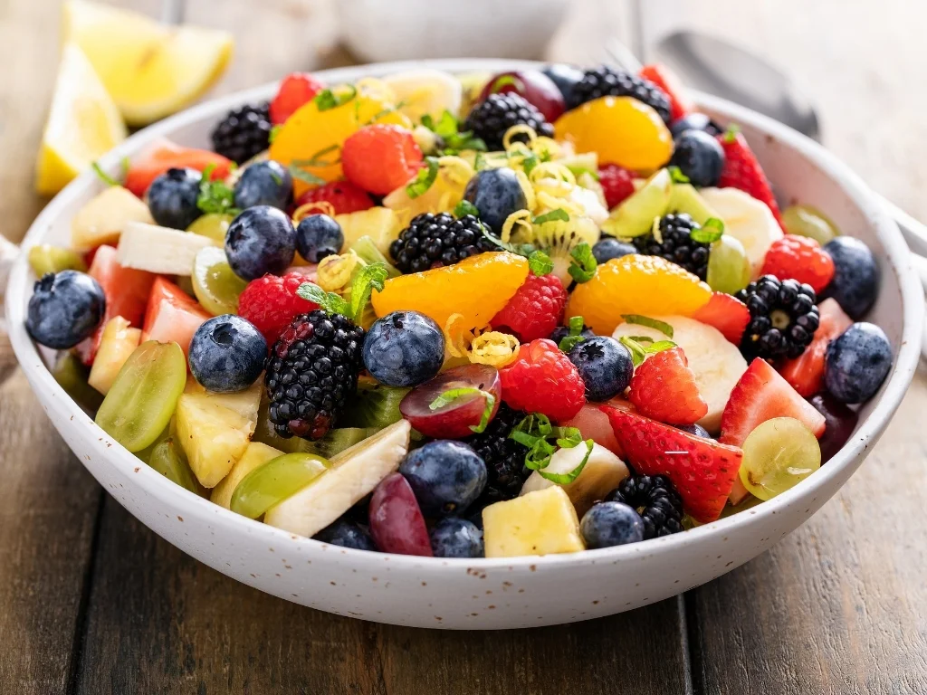 Fruit salad on a wooden table with berries and honey dressing